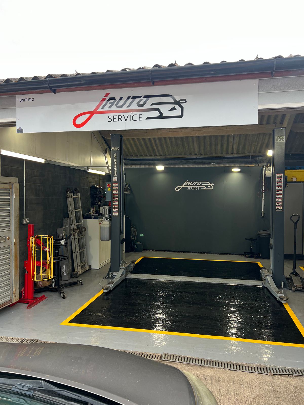 J Auto Service workshop bay with branded signage and vehicle lift